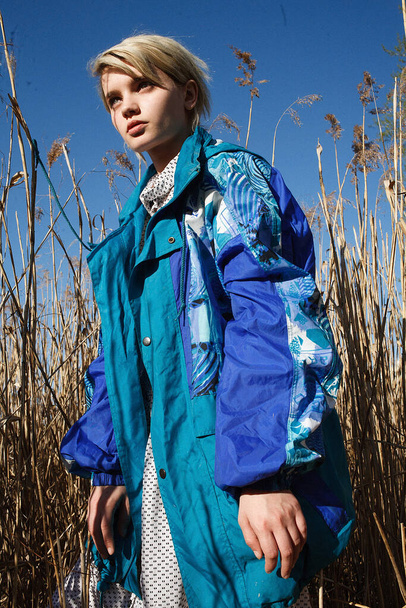 fiatal vonzó kaukázusi nő rövid haj kék kabát napsütéses napon - Fotó, kép