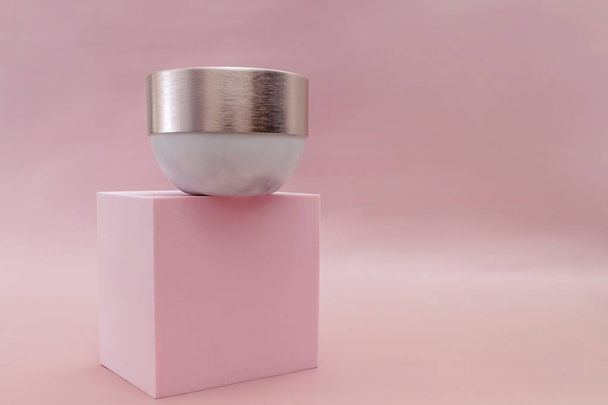 Mockup moisturizer cream in jar standing on pedestal on pastel pink background - Φωτογραφία, εικόνα