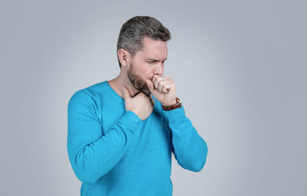 zralý muž s vousem má kašel trpí bolestí v krku na šedém pozadí, mužské zdraví. - Fotografie, Obrázek