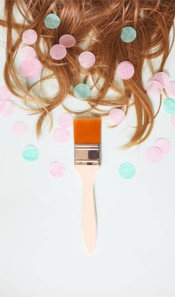 Сверху мягкие шелковистые волосы на белом фоне с кистью в сторону все в разрозненных конфетти - Фото, изображение