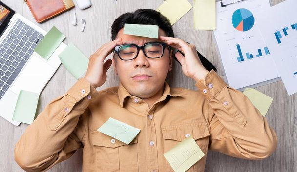 aziatische man liggend op stapel van papieren en gevoel moe van werk - Foto, afbeelding