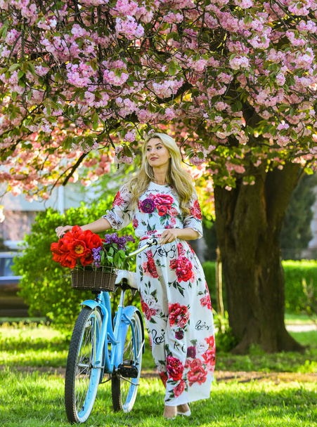 Sakura season. Tourism concept. Transportation and travel. Girl long dress retro cruiser bicycle sakura tree. Spring holidays. Woman with tulips bouquet. Sakura tree blooming. Romantic bike ride - Foto, Bild