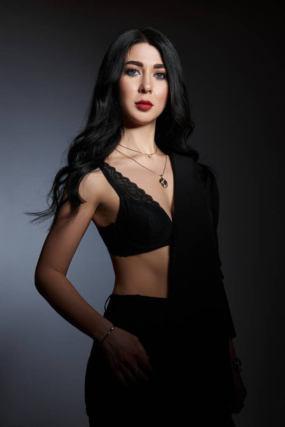 Sexy beauty brunette woman in black jacket poses in studio. Elegant girl with beautiful natural makeup - Fotó, kép