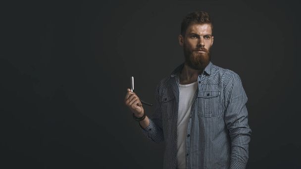 Portrait of bearded man with straight razor - 写真・画像