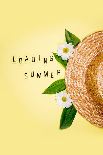 Womens summer straw hat on yellow background top view flat lay copy space. Summer travel vacation concept, single item. Text SUMMER from letters and field chamomiles flowers on yellow. - Foto, immagini