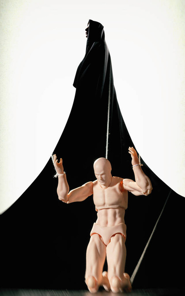 Meervoudige belichting. Silhouet van vrouw in mantel en marionet aan de touwtjes. Begrip "controle". - Foto, afbeelding