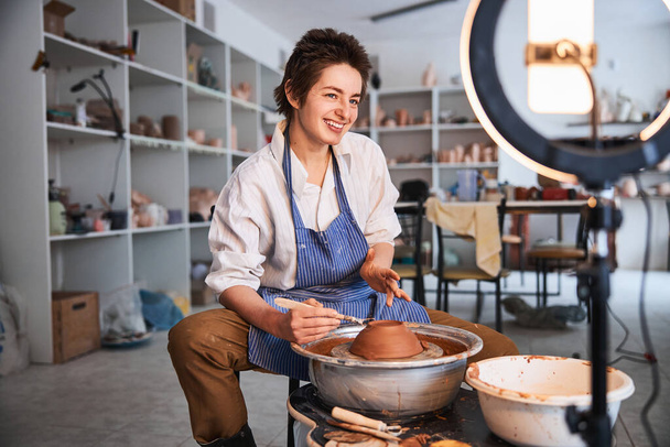 Cheerful ceramist smiling during work on clay product - Fotoğraf, Görsel