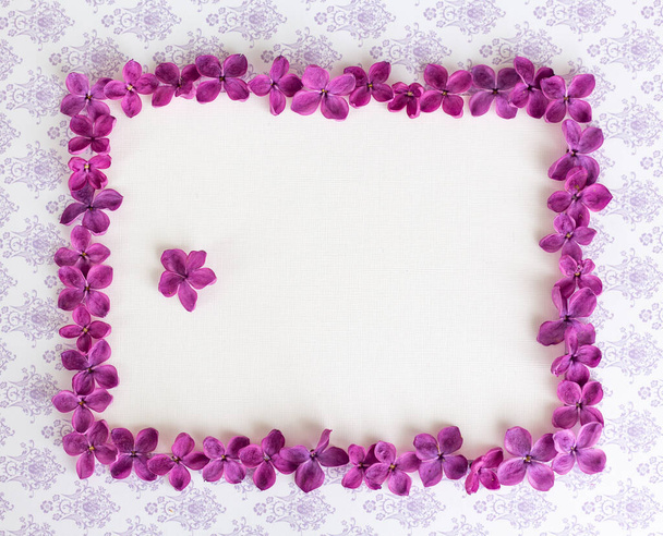 ライラック紫色の花とテーブルの上に空白のコピースペースを持つ背景。バイオレットの花。ホワイトペーパーのトップビュー、フラットレイアウト、最小限のスタイル。目を覚ませ. - 写真・画像