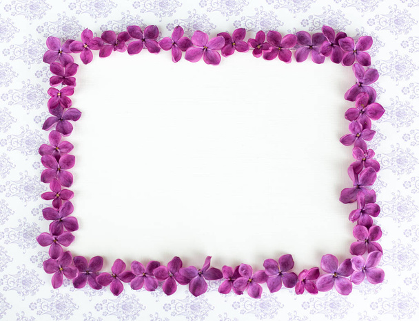 ライラック紫色の花とテーブルの上に空白のコピースペースを持つ背景。バイオレットの花。ホワイトペーパーのトップビュー、フラットレイアウト、最小限のスタイル。目を覚ませ. - 写真・画像