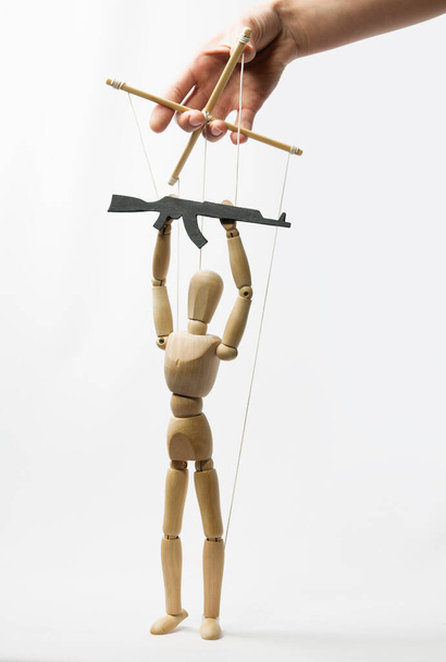 Marionette on the strings with rifle in the human hand. Concept of control. - Photo, Image