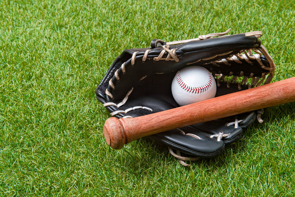 Baseball bat, glove and ball on green grass field. Sport theme background with copy space for text and advertisment - Photo, Image