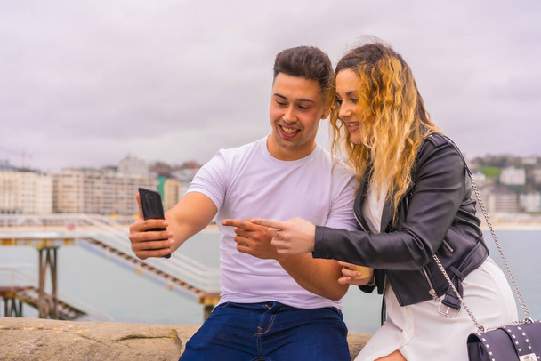 Lifestyle of a Caucasian couple sightseeing and enjoying the vacations. Taking a selfie photo with the mobile phone - 写真・画像