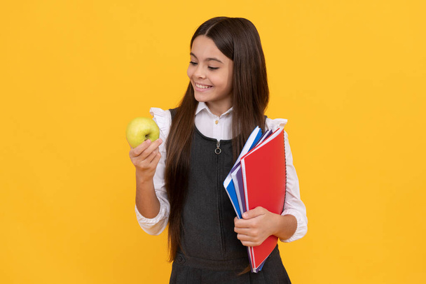 Välipalan aika. Onnellinen tyttö katso omena tilalla koulukirjoja. Koulun välipala. Elintarvikekasvatus - Valokuva, kuva