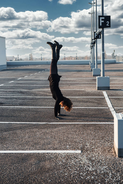 young brunette woman making a handstand in empty parking lot outdoors - Foto, Imagem