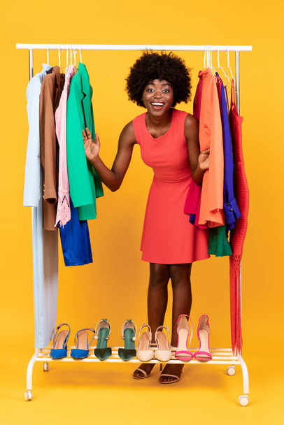 Zwarte winkelverslaafde dame op het winkelen poseren met kleding Rail, Studio - Foto, afbeelding