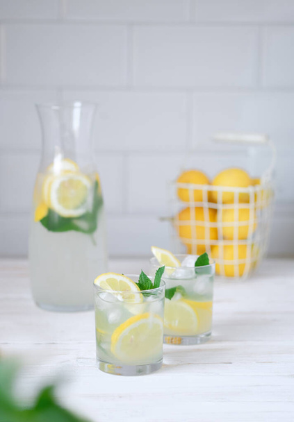 Fresh lemon lemonade with mint in bottle on kitchen table with ingredients. healthy nutrition diet concept. White background - Fotó, kép