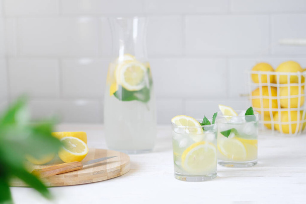 Limonada de limón fresco con menta en botella en la mesa de la cocina con ingredientes. concepto de dieta saludable nutrición. Fondo blanco - Foto, Imagen