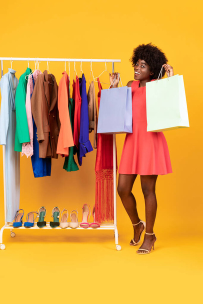 Izgatott afrikai hölgy Showing Shopper táskák álló stúdió, függőleges - Fotó, kép