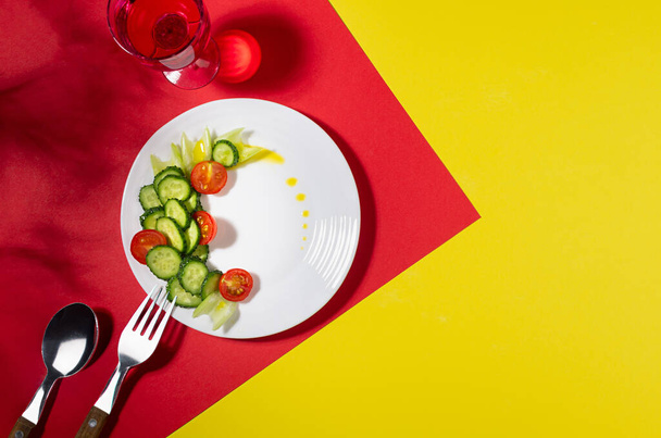 Wellness food - fresh salad of tomato, cucumber, celery on white plate in hard light with shadow with drink on red, yellow background. - Fotó, kép
