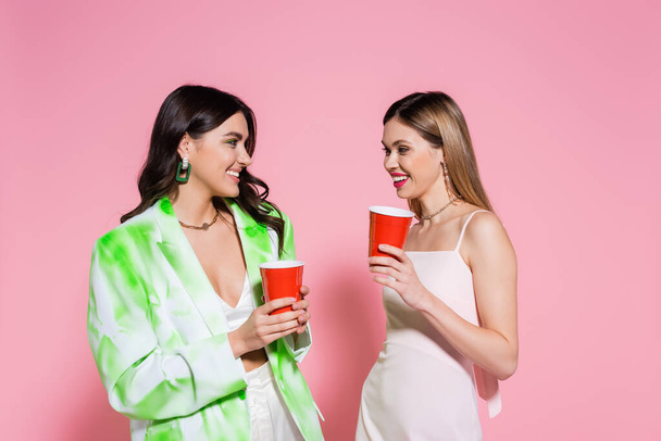 Young friends holding plastic cups on pink background  - Foto, Bild