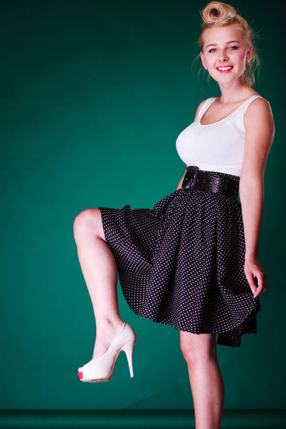 Fashion, clothing, disguise concept. Lovely young pin up girl in vintage hairstyle wearing retro black and white dress with big belt. Studio shot on green background - Foto, Imagen