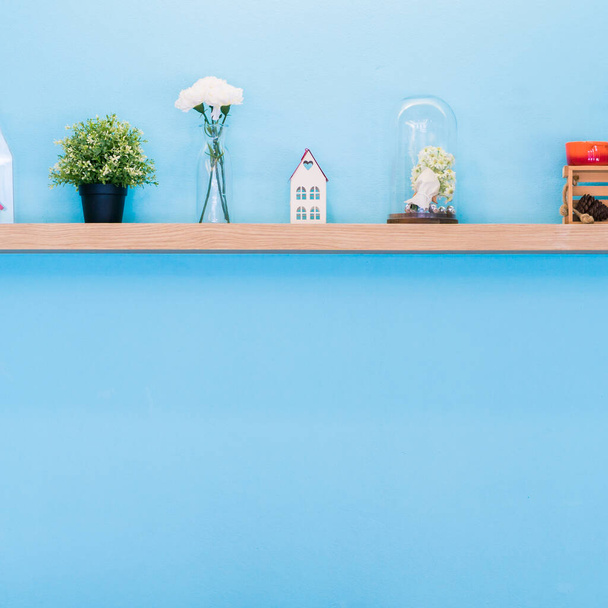 Haus Spielzeug und Blumenvase auf Holzregal Home Dekoration, kreative blaue Wand mit sauberem Kopierraum für Design - Foto, Bild