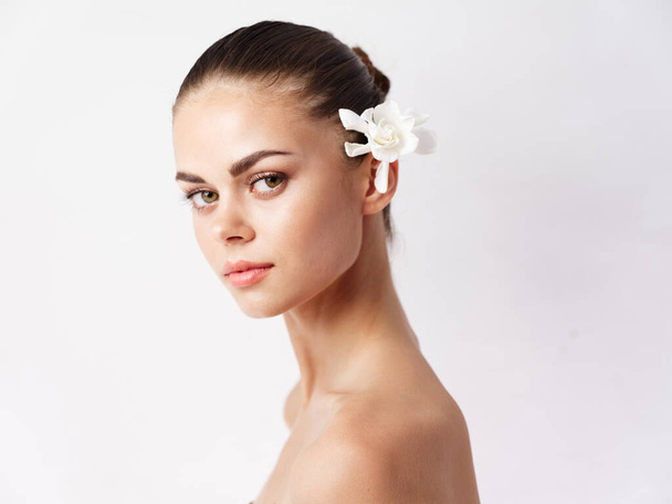 woman with bare shoulders makeup white flower in hair isolated background - Foto, afbeelding