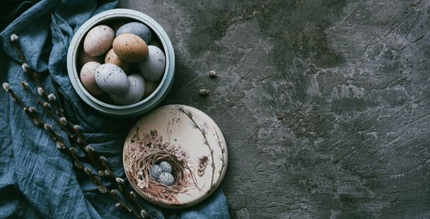 Vintage background with easter eggs in wooden plate on a concrete background. Napkin and spring branches. Top view with copy space. - Foto, imagen