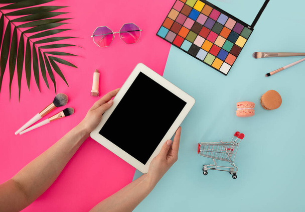 Mockup com tela de tablet em branco em mãos femininas e vários cosméticos de beleza, óculos de sol em fundo colorido, vista superior - Foto, Imagem