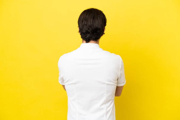 Mladý běloch izolovaný na žlutém pozadí v zadní poloze - Fotografie, Obrázek