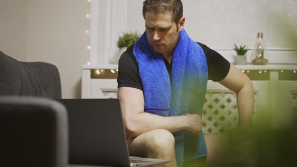 De man kijkt naar een oefening op de laptop. Sportactiviteiten thuis. - Video