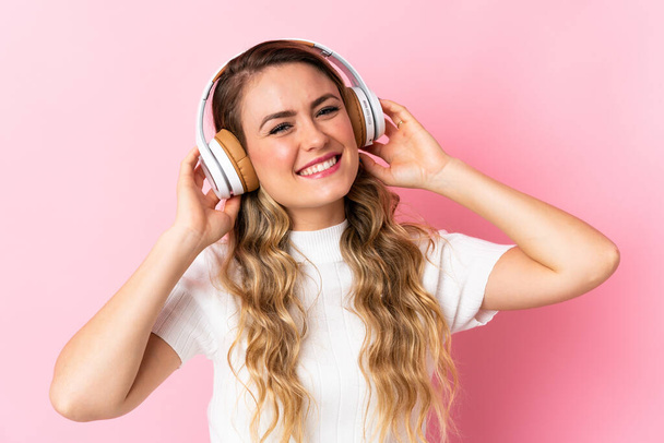Νεαρή Βραζιλιάνα απομονωμένη σε ροζ φόντο ακούγοντας μουσική - Φωτογραφία, εικόνα