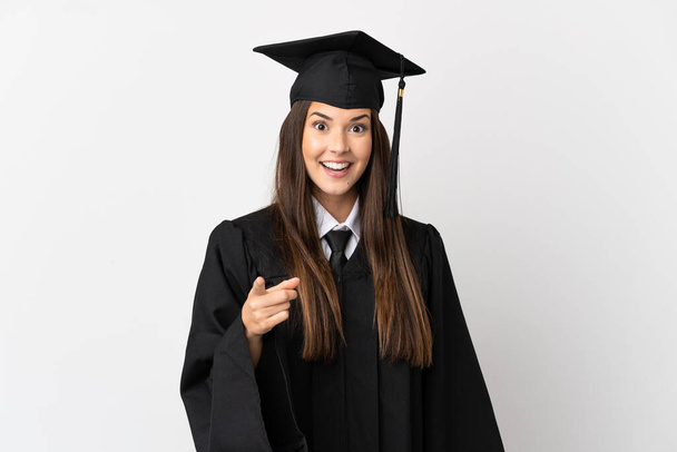Teenager Brazilian university graduate over isolated white background surprised and pointing front - Fotó, kép