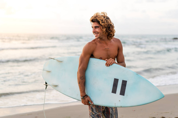 Young caucasian man get up early to  doing surf at sunrise - Photo, image