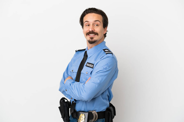 Jonge politieman over geïsoleerde achtergrond wit met armen gekruist en gelukkig - Foto, afbeelding