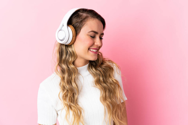 Young brazilian woman isolated on pink background listening music - Foto, Imagem