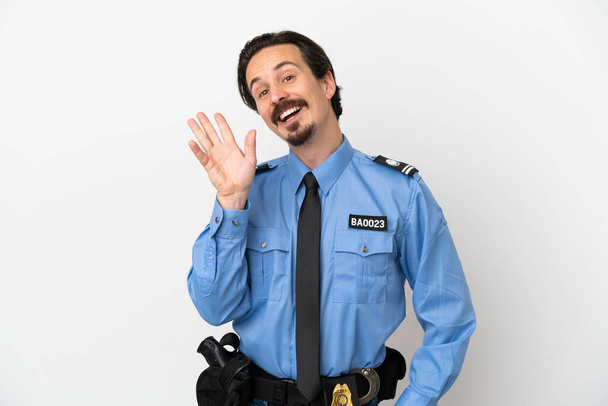 Mladý policista přes izolované pozadí bílé salutování s rukou s veselým výrazem - Fotografie, Obrázek