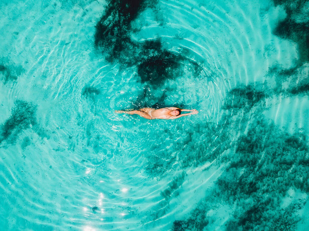 Γυμνή γυναίκα που επιπλέει και χαλαρώνει στον γαλαζοπράσινο ωκεανό. Αεροφωτογραφία, κορυφαία προβολή - Φωτογραφία, εικόνα
