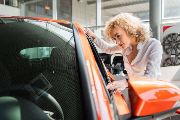Curly woman looks car at the dealership - Photo, Image