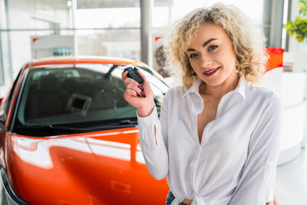 Portrait of beautiful woman with key in hands near her new car - Фото, изображение