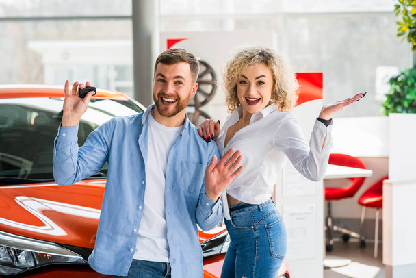 Happy couple in car dealership on the background of their new car - Foto, Imagen