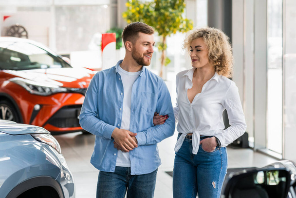 Young couple walks through the car dealership in search of a new car - Foto, afbeelding