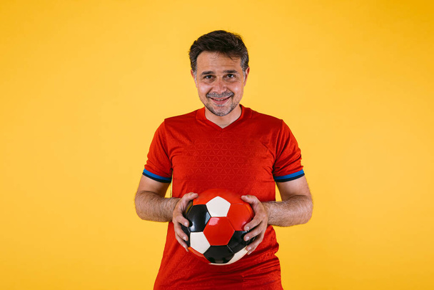 Fußballfan mit rotem Trikot und Ball in der Hand - Foto, Bild