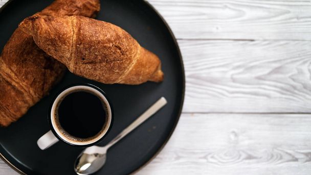 Flat lay of freshly baked croissants with a hot coffee on wooden table  simple morning breakfast copy space - Foto, Imagen