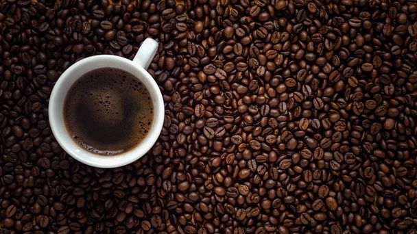 Flache Lage der Kaffeetasse auf dunkel gerösteten Arabica-Kaffeebohnen Hintergrund Kopierraum - Foto, Bild