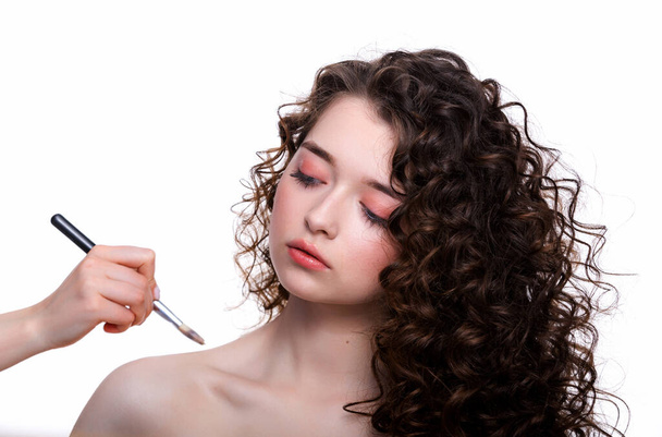 Artista de maquiagem suaviza o tom da pele no corpo bela jovem no salão de beleza faz um cabelo ondulação e maquiagem - Foto, Imagem