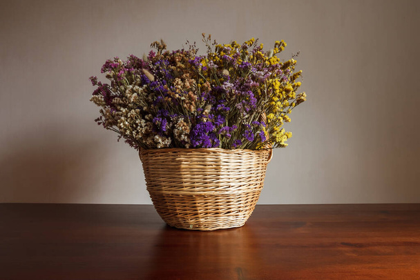 Natureza morta com um buquê de flores secas em uma cesta feita de palha - Foto, Imagem