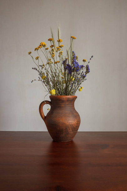 Stilleven met een boeket gedroogde bloemen in een keramische pot - Foto, afbeelding