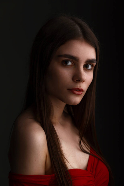 Gros plan de belle jeune femme séduisante visage avec maquillage naturel sur fond de studio sombre - Photo, image