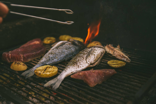 cooking fish and potatoes on grill outdoors - Zdjęcie, obraz